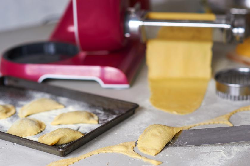 Die Auberginen-Ravioli mit Walnusspesto liegen fertig gefüllt auf einem Backblech und der Arbeitsplatte.