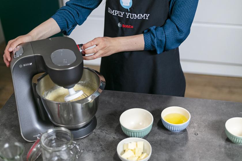 Teigzutaten werden in der Rührschüssel einer Küchenmaschine glatt gerührt.