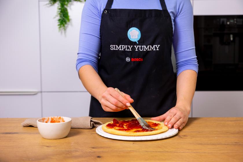 Erdbeermarmelade wird auf den Mürbeteigboden für die Benjamin Blümchen Torte verstrichen.