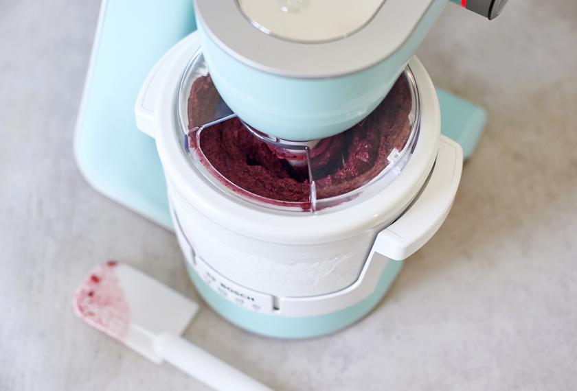 Die Masse für den Blaubeer Frozen Yoghurt gefriert in einer Eismaschine.