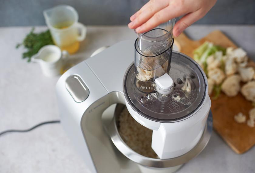 Gemüse für das Blumenkohl Risotto wird in einer Küchenmaschine gerieben.