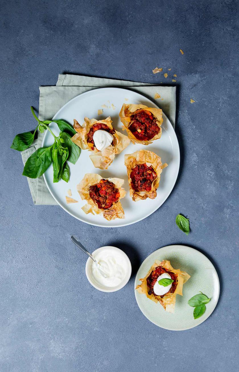 Mehrere Bolognese-Törtchen mit Knusperteig auf einem Teller.