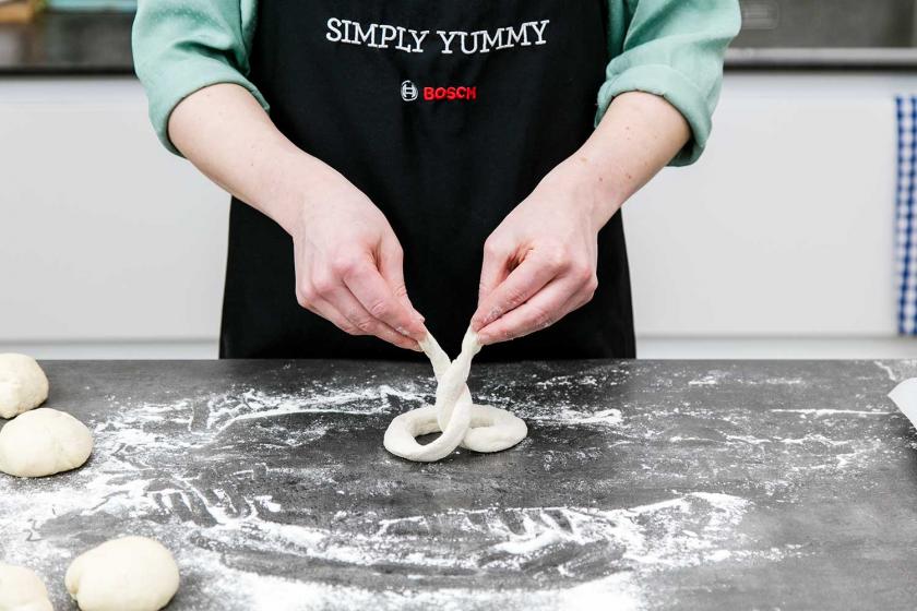 Der Teig für die Brezel wird umeinandergezwirbelt.
