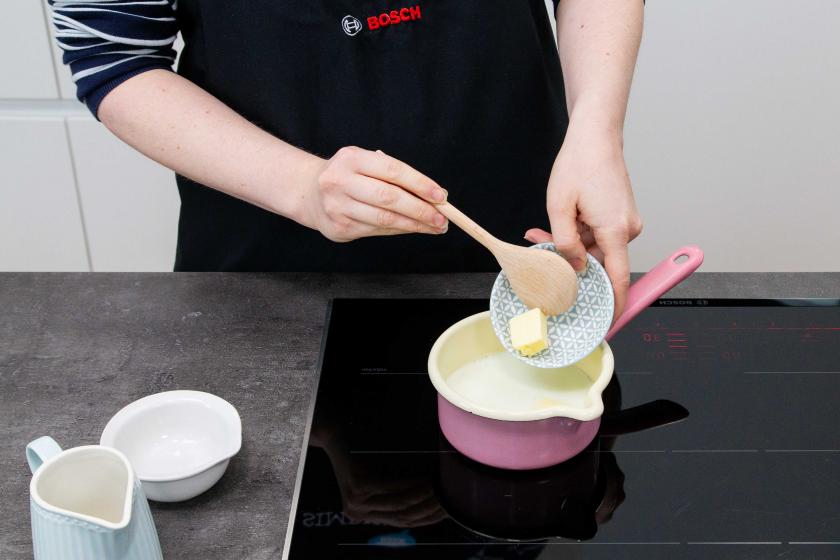 Für die Burger Buns Brioche wird Butter in einen Topf mit Milch gegeben.