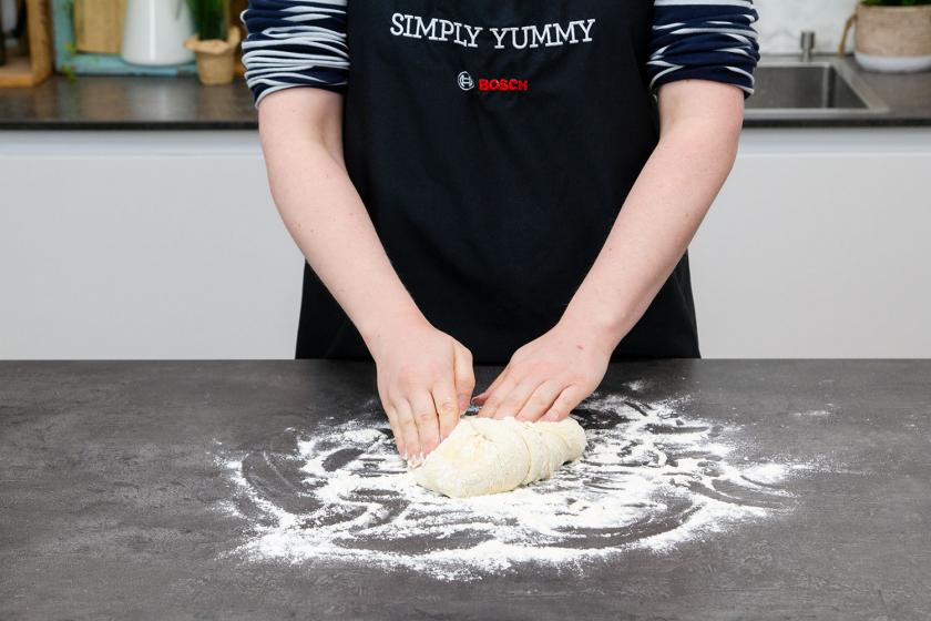 Der Teig für die Burger Buns Brioche wird auf einer bemehlten Arbeitsfläche geknetet.