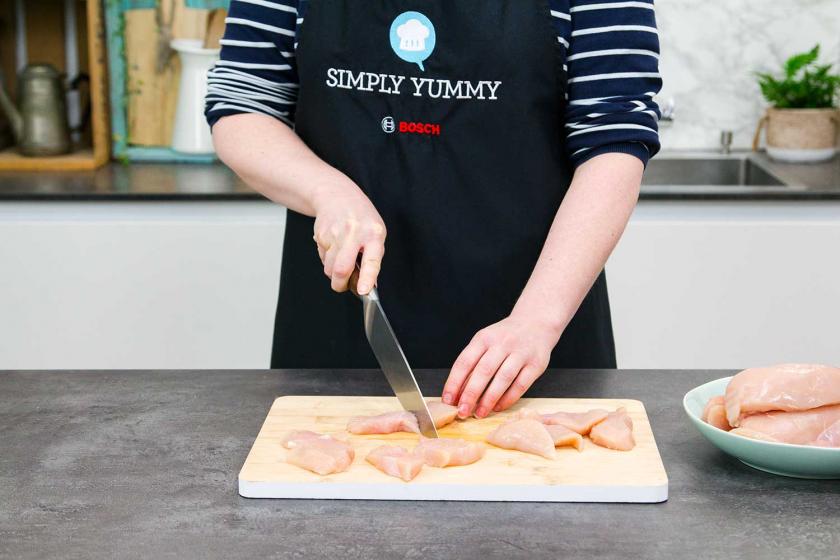 Das Fleisch für die Chicken Nuggets wird in Stücke geschnitten.
