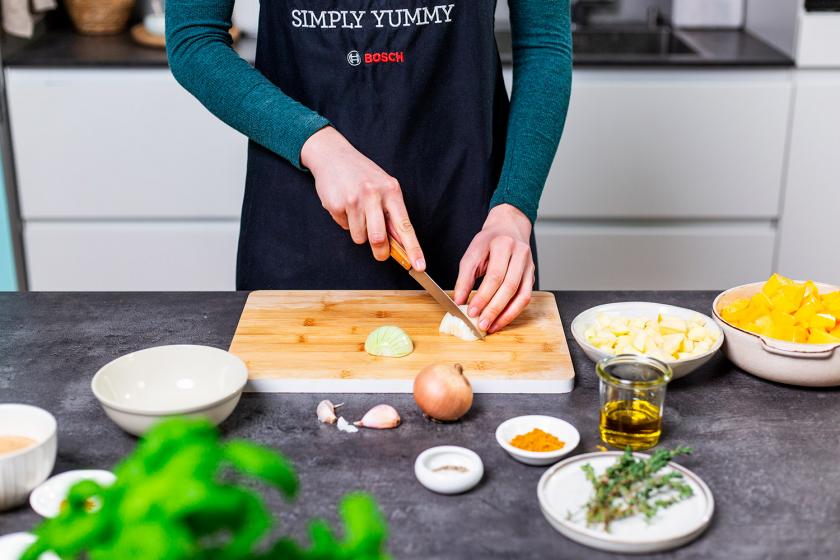 Zwiebel wird auf einem Holzbrett gewürfelt.