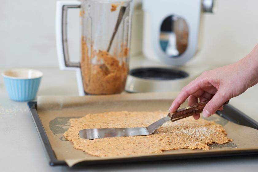 Die Masse des Cracker Rezepts wird auf einem Backblech glattgestrichen.