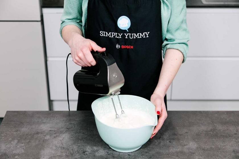 Sahne wird mit einem Handmixer aufgeschlagen.