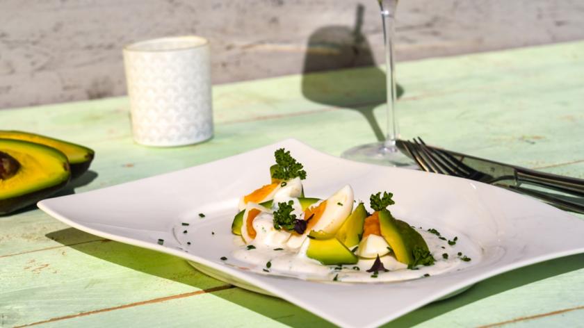 Eiersalat ohne Mayo, aber mit Avocadospalten und Joghurtdressing angerichtet auf einem Teller