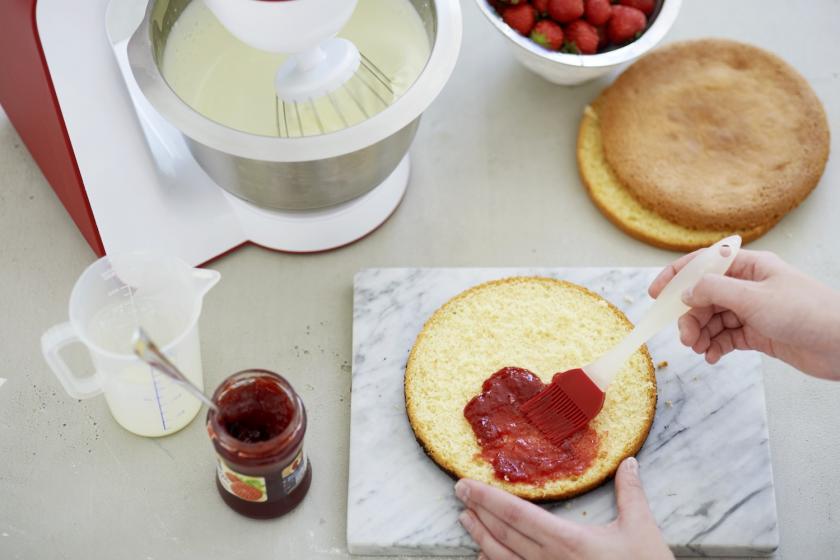 Der Boden für Erdbeer-Sahne-Torte wird mit Marmelade bestrichen.