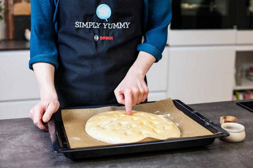 Fladenbrot wird mit den Fingern eingedrückt.