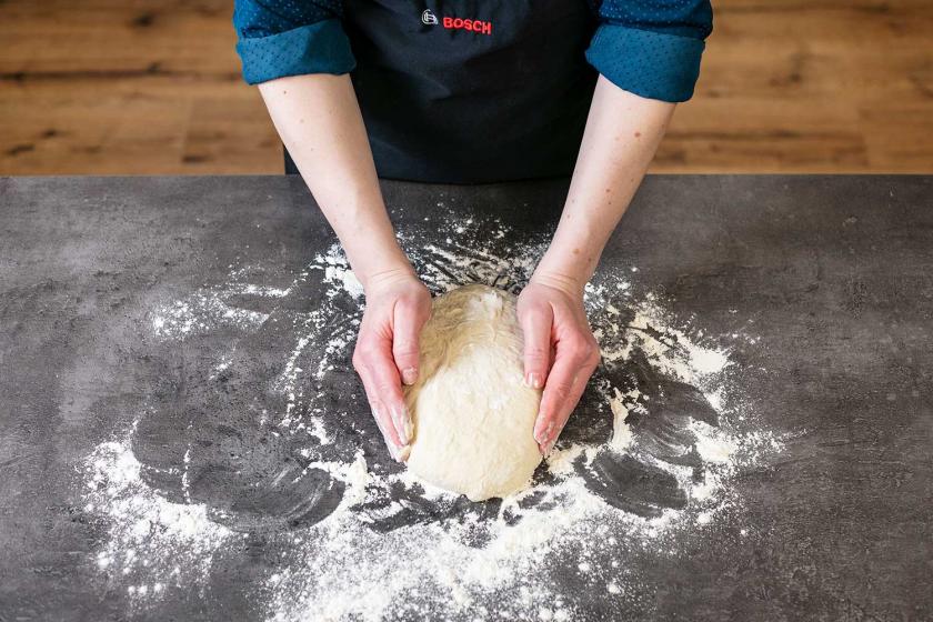 Fladenbrot wird auf einer bemehlten Arbeitsfläche geformt.
