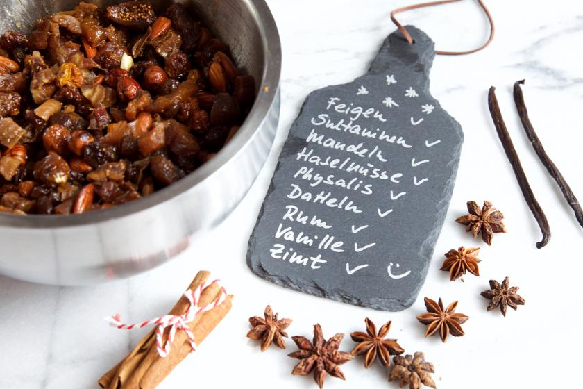 Für den Früchtekuchen werden Sultanien in einer Schüssel mit Rum eingeweicht. Daneben eine Tafel mit den Zutaten aufgelistet. 