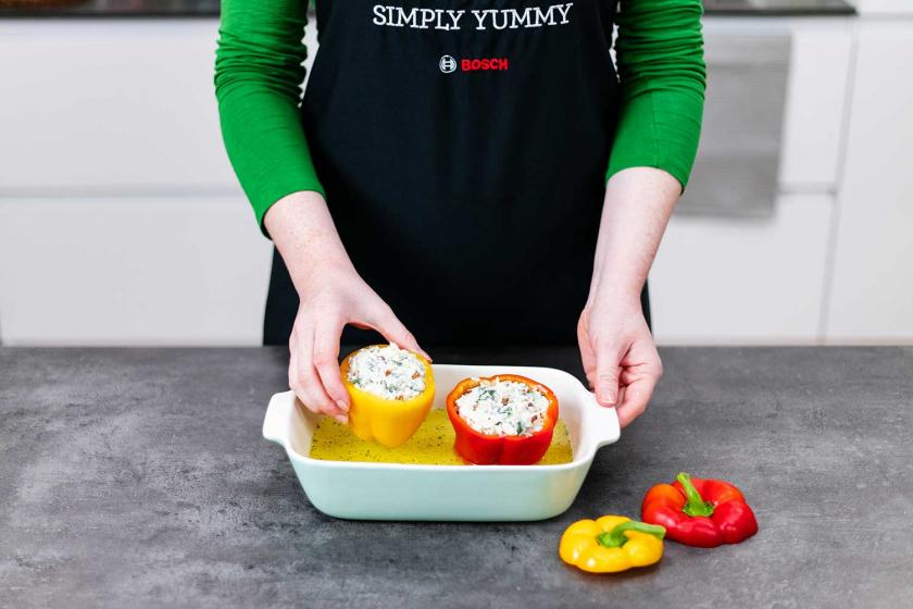 Gefüllte Paprika mit Reis werden in eine Auflaufform gegeben.