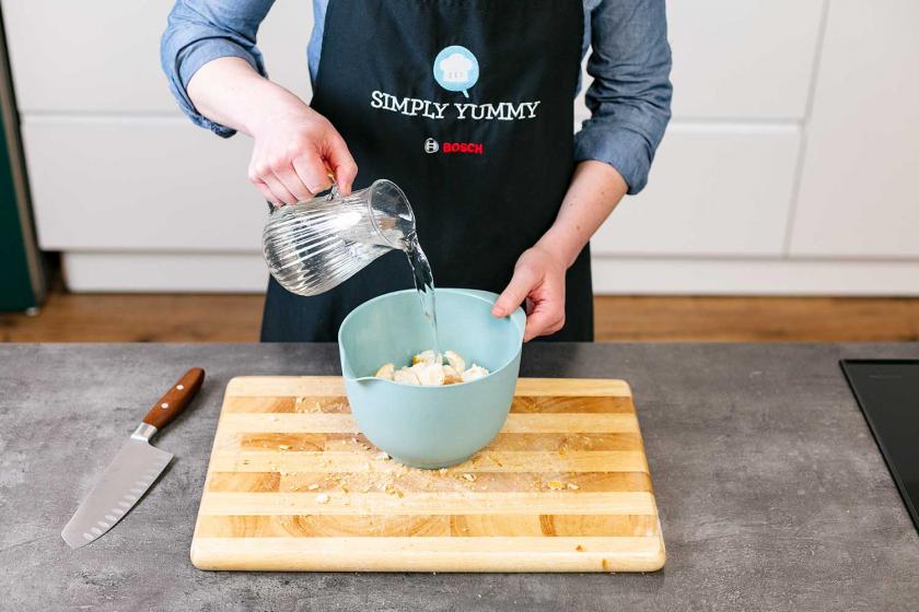 Brotwürfel in einer Schüssel werden mit Wasser übergossen.