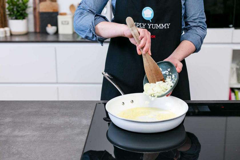 Zwiebeln werden in eine Pfanne gegeben.