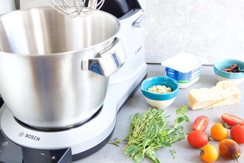 Der teig für die Mini-Muffins mit Tomaten wird in einer Küchenmaschine zubereitet. Drumherum Tomaten, Kräuter und Co.