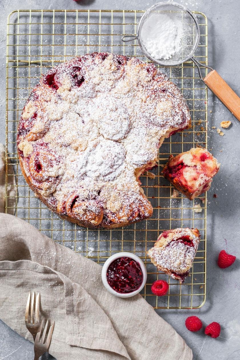 Himbeer-Schnecken mit Puderzucker angebrochen auf einem Kuchengitter.