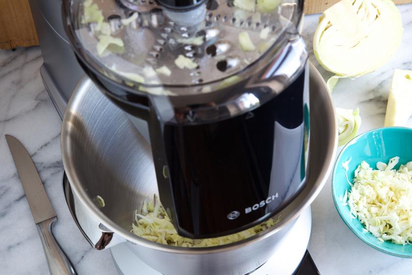 Für Hot Dogs mit Sauerkraut wird der Weißkohl in einer Küchenmaschine geraspelt.