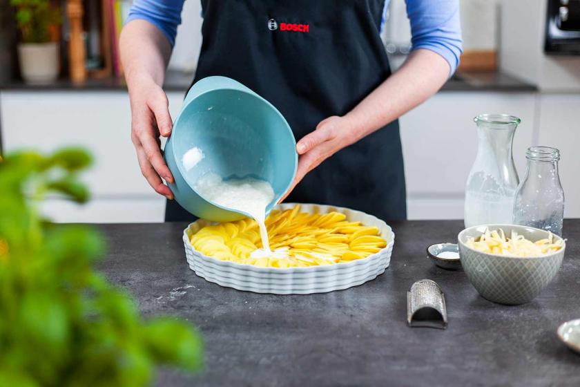 Sahneguss über Kartoffelgratin in Auflaufform geben.