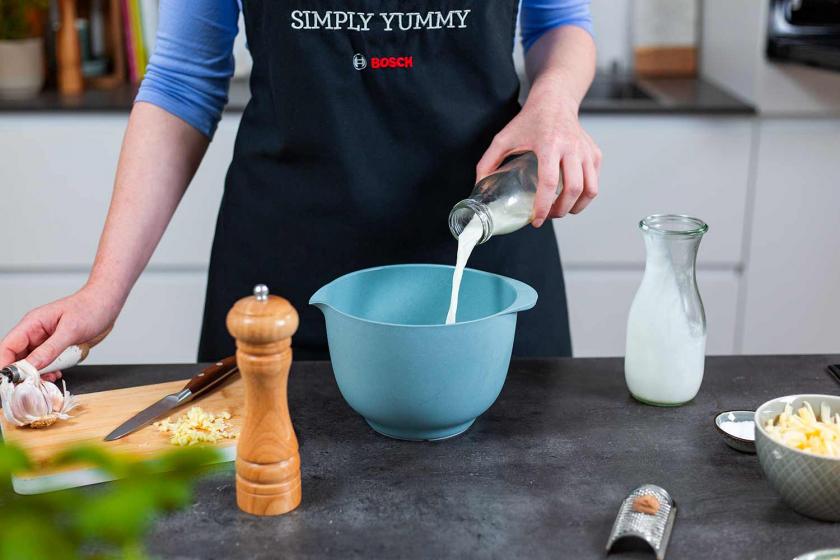 Sahne wird auf Kartoffelgratin gegossen.