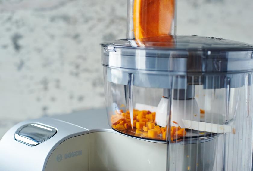 Für den Nudelauflauf mit Kürbis und Spinat wird Kürbis in einer Küchenmaschine gewürfelt.