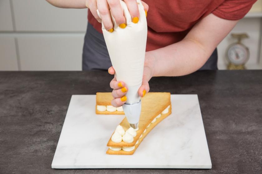 Mit einem Spritzbeutel  wird die Creme für den Number Cake verteilt.