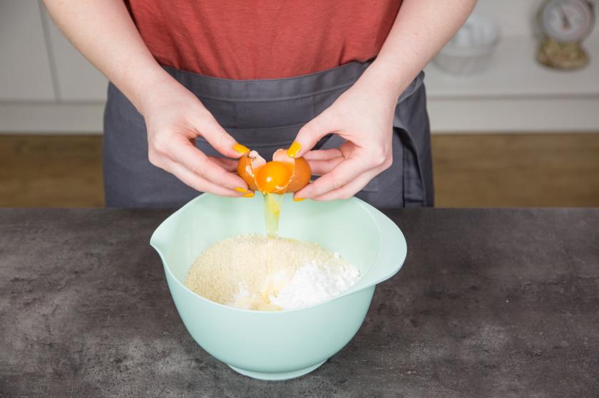 Ein Ei wird zu den restlichen Zutaten für den Number Cake in die Schüssel gegeben.