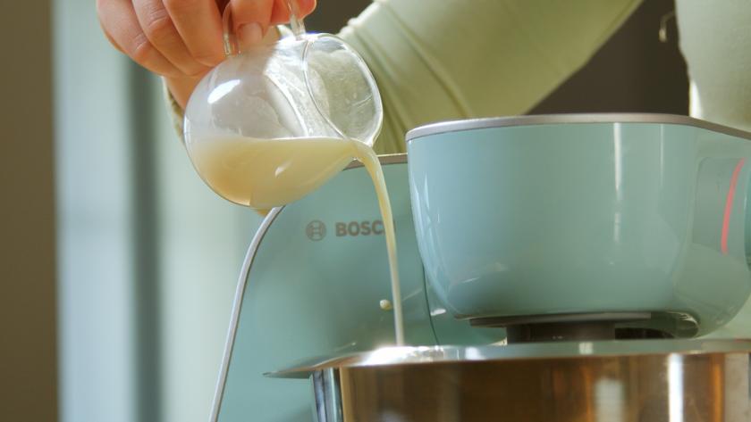 Milch wird in die Rührschüssel einer Küchenmaschine gegeben.