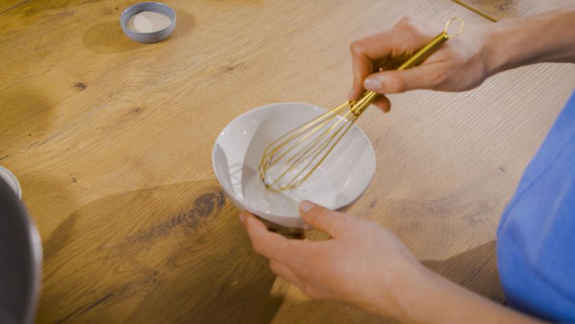 Milch wird in einer kleinen Schüssel mit einem Schneebesen verrührt.