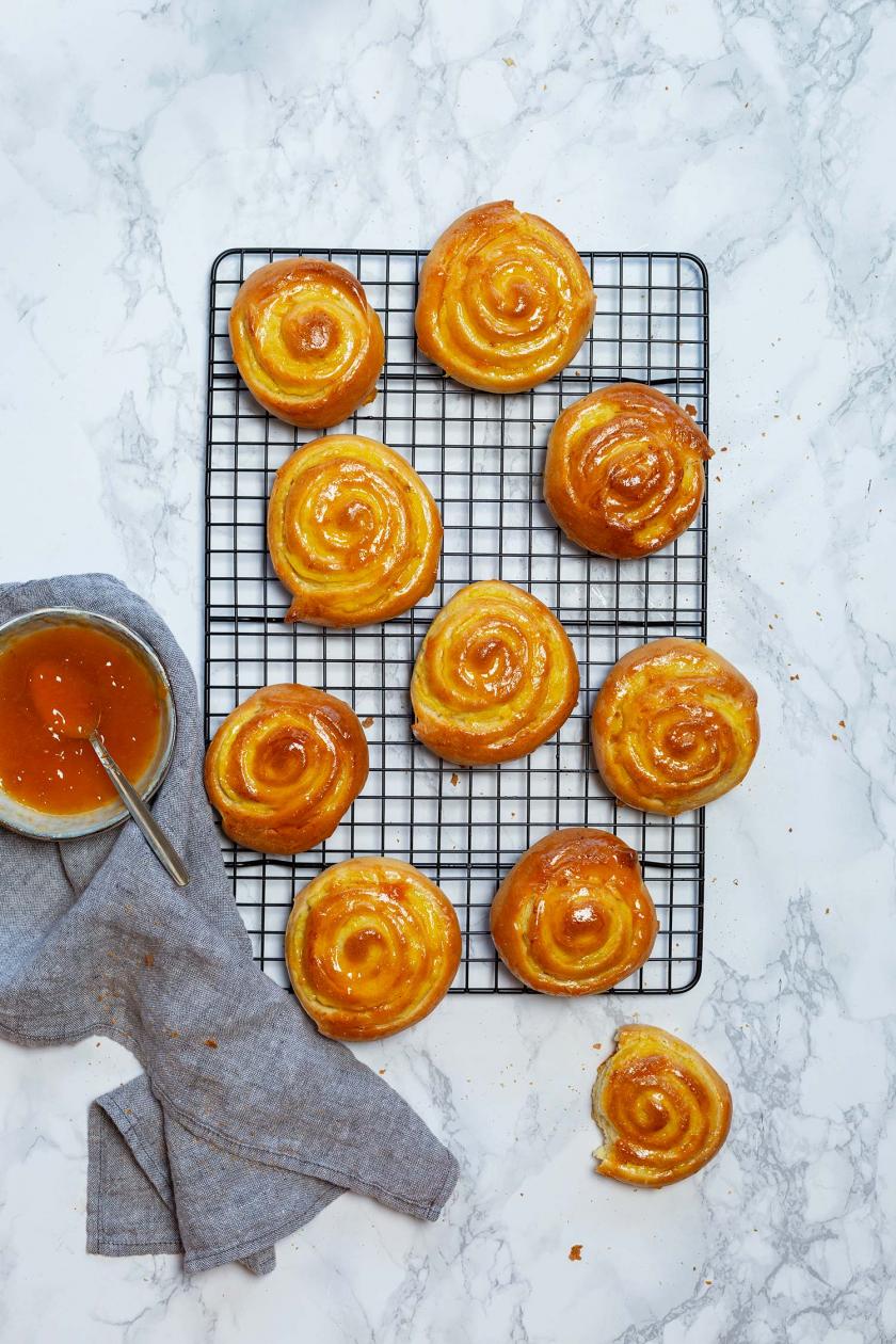 Mehrere Puddingschnecken auf einem Kuchengitter, daneben Marmelade in einer Schale.