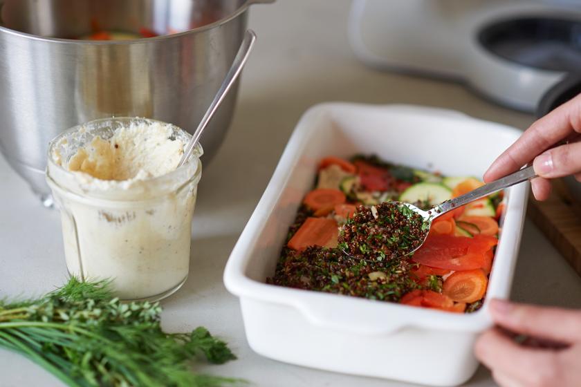 Quinoa-Auflauf wird mit Gemüse und Co. in einer Auflaufform geschichtet.