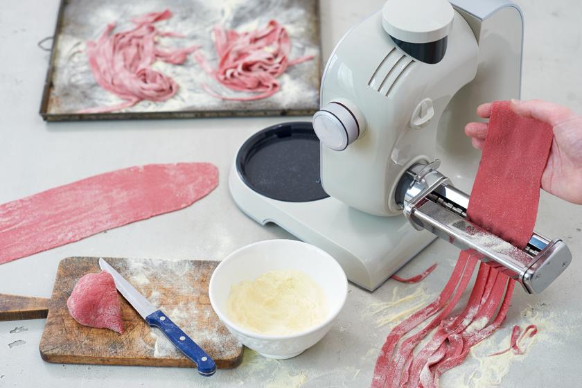 Der Teig für die Rote Bete Nudeln wird mit einer Nudelmaschine zu Tagliatelle verarbeitet.