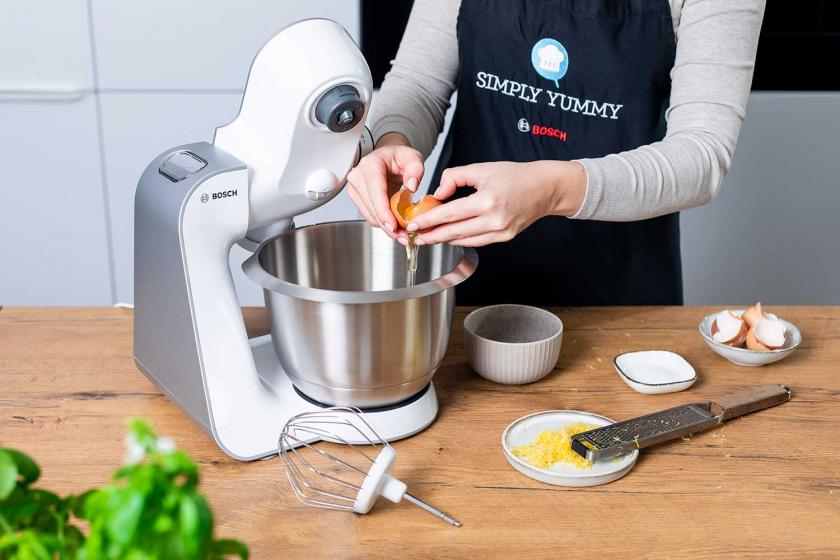 Ei wird in die Rührschüssel einer Küchenmaschine gegeben.