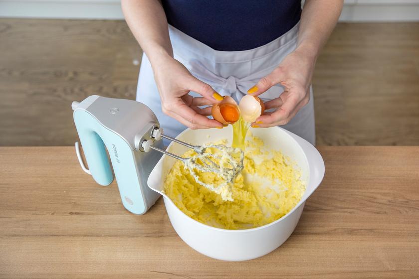 Ein Ei wird zum Sandkuchenteig gegeben.
