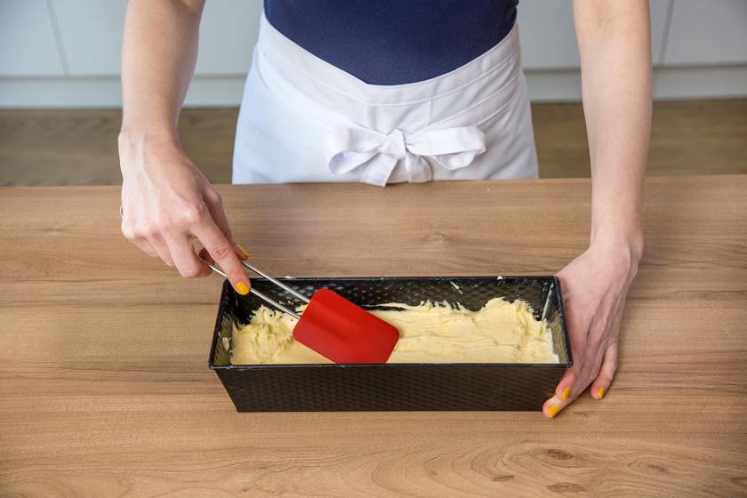 Der Teig für den Sandkuchen wird mit einem Teigschaber glatt gestrichen.