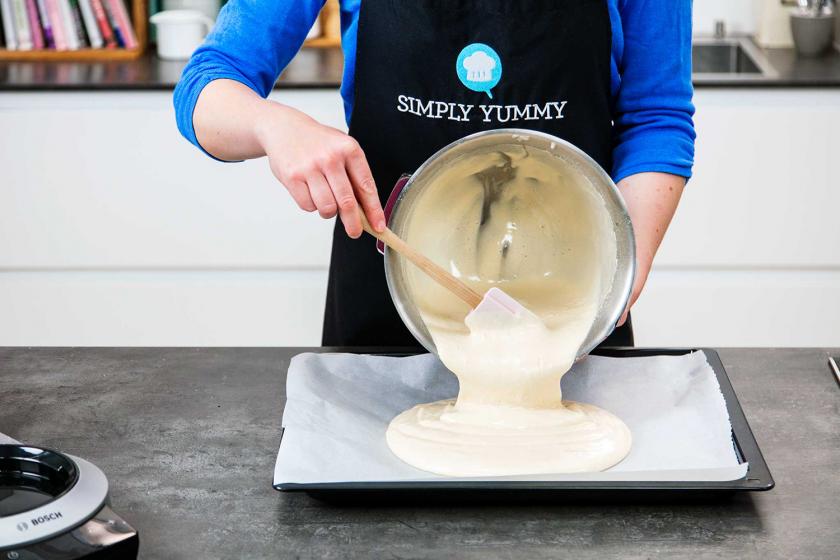 Für das Schneebälle Rezept wird der Biskuitteig auf einem Blech verteilt.