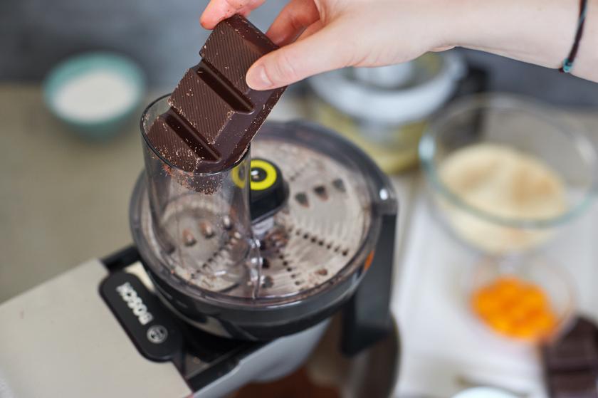 Zartbitterschokolade wird für den Orangen-Schoko-Kuchen gerieben.