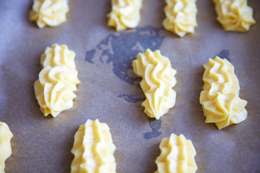 Der Teig der Schokoladen-Eclairs mit Salzkaramell wurde auf ein Backblech gespritzt.