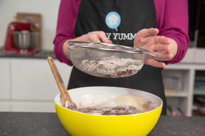 Für den Biskuit der Schwarzwälder Kirschtorte wird Kakao in eine Rührschüssel gesiebt.