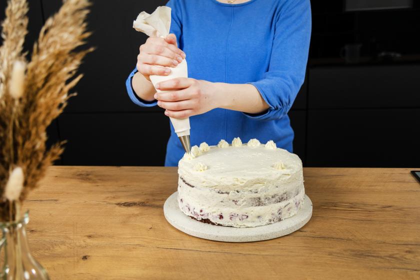 Schwarzwälder Kirschtorte wird mithilfe einer Tülle mit Tupfen verziert