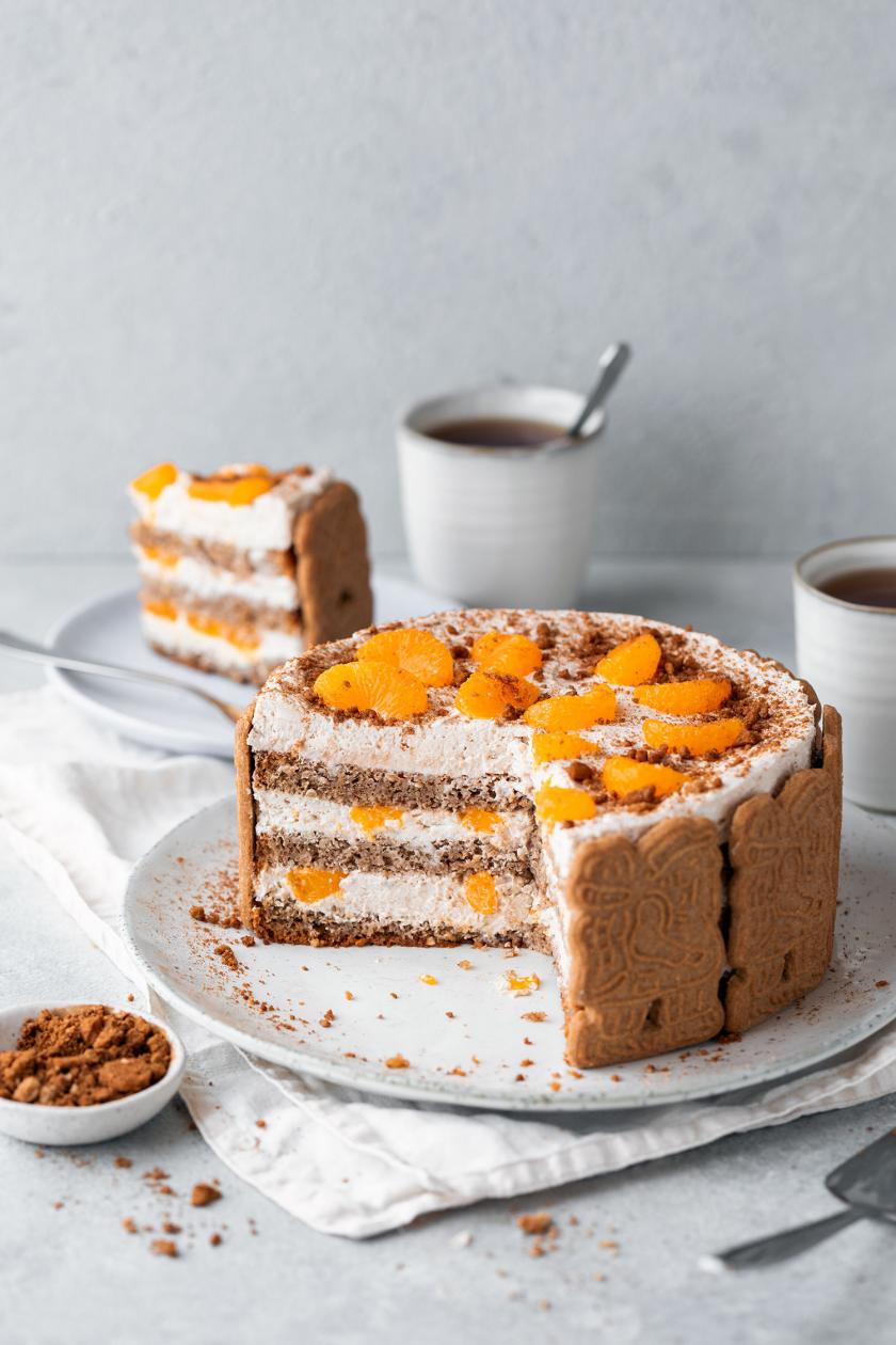 Spekulatius Torte mit Mandarinen angeschnitten auf einer Tortenplatte, close up auf die Füllung mit Mandarinen und Creme