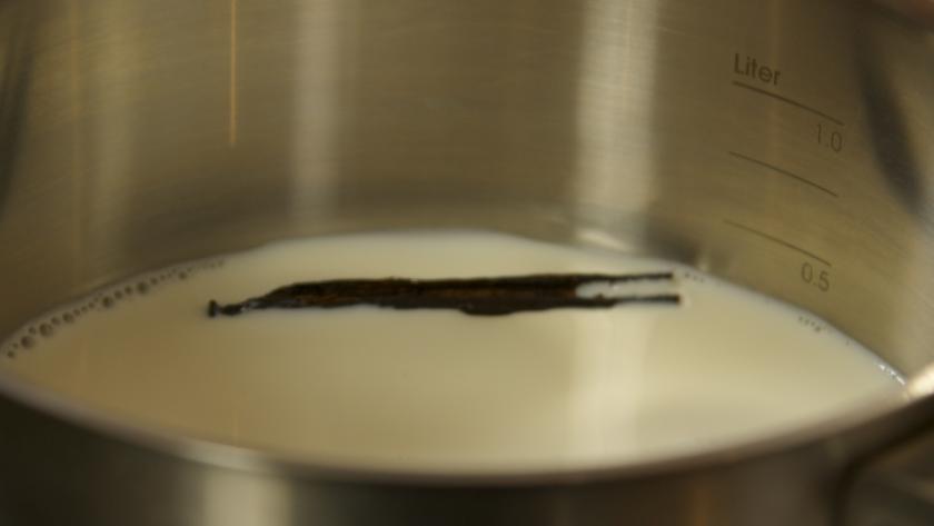 Vanilleschote liegt in Milch in einem Topf.