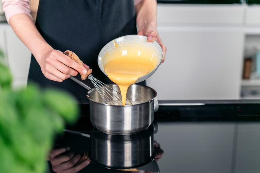 Eimasse wird zu Sahne in einen Topf gegeben.