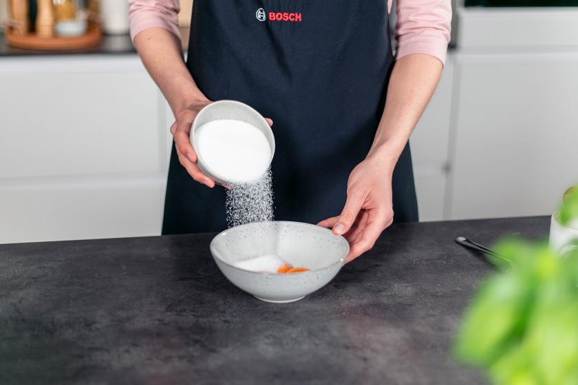 Zucker wird zu Eigelb in eine Schüssel gegeben.