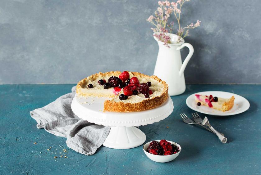 Veganer Käsekuchen auf einer Etagere. Ein Stück ist herausgeschnitten.