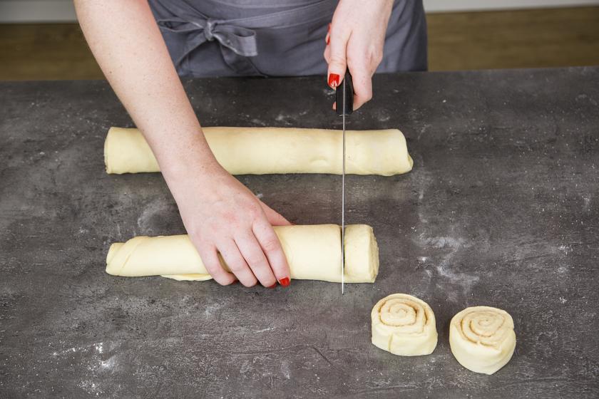 Der Teig für die Zimtschnecken wurde zusammengerollt und wird in Stücke geschnitten.
