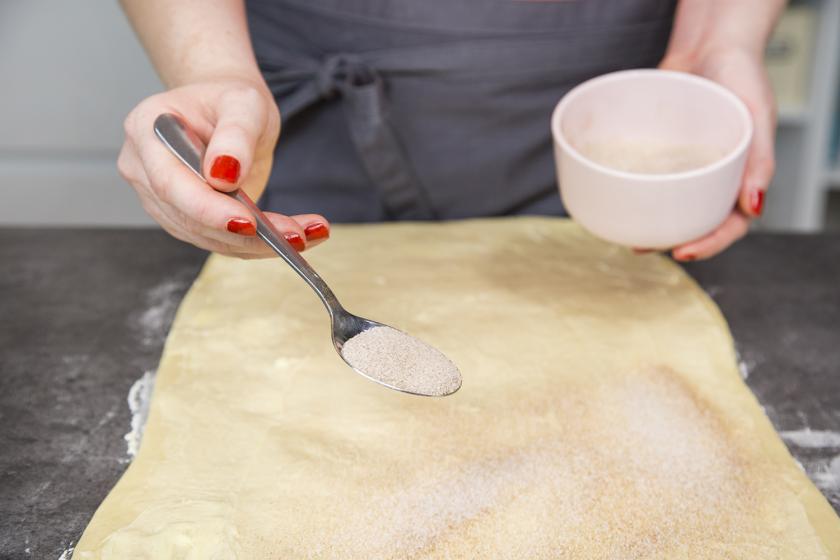 Der Teig für Zimtschnecken wird mit Zimt und Zucker bestreut.