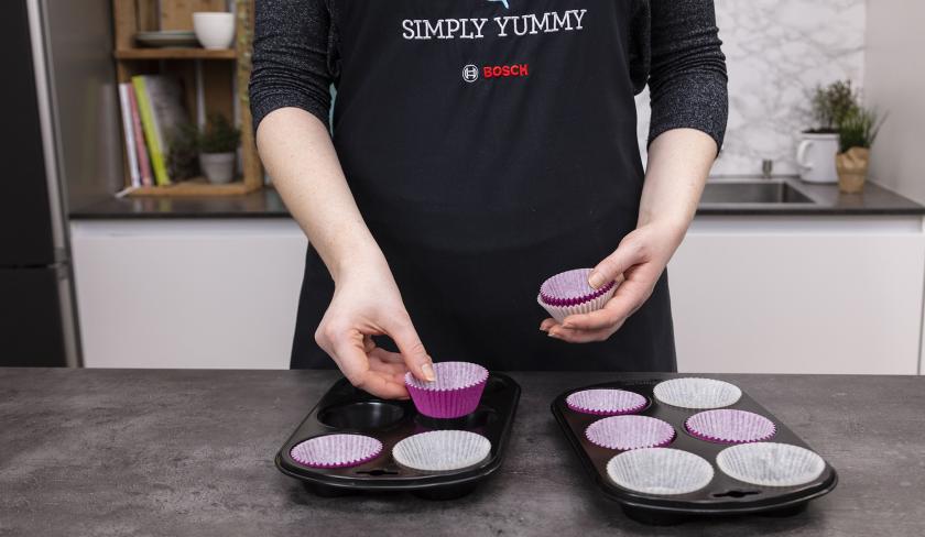 Muffinblech wird mit Papierförmchen ausgekleidet.